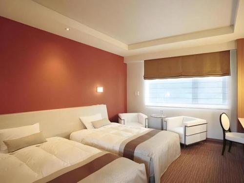 a hotel room with two beds and a window at Sakuraan Kawaguchiko Hotel in Fujikawaguchiko