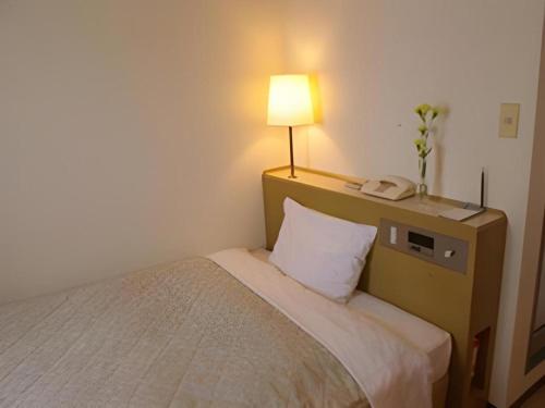 a bedroom with a bed with a lamp and a phone at Isehara Green Palace Hotel in Isehara