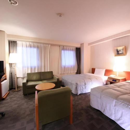 a hotel room with two beds and a couch at Centia Hotel Naito in Kofu