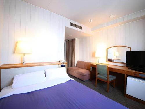 a hotel room with a bed and a desk and a television at Centia Hotel Naito in Kofu