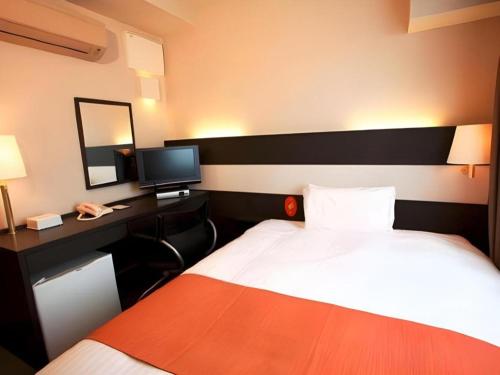 a hotel room with a bed and a desk with a phone at AI HOTEL OYAMA in Sano