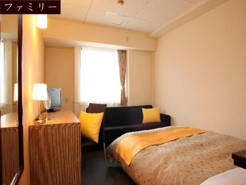 a bedroom with a bed and a desk and a window at Hotel 1-2-3 Kofu Shingen Onsen in Kofu