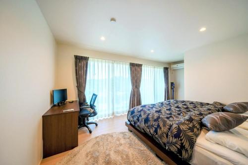 a bedroom with a bed and a desk and a television at 湘南sajima stay in Yokosuka