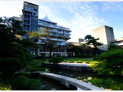a building with a bridge in front of a river at Hotel Tokoen in Yonago