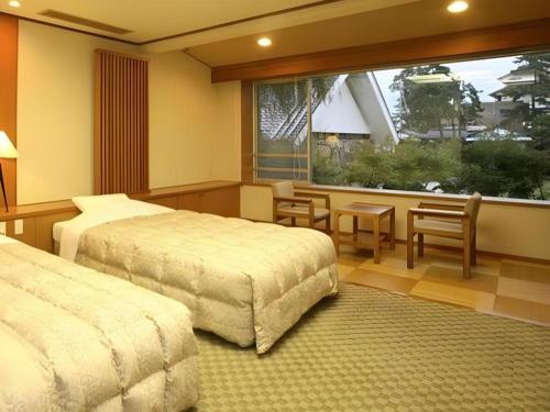 a bedroom with two beds and a table and a window at Hotel Tokoen in Yonago