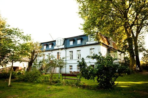 a large white house with a bench in the yard at Gut Boltenhof in Fürstenberg-Havel