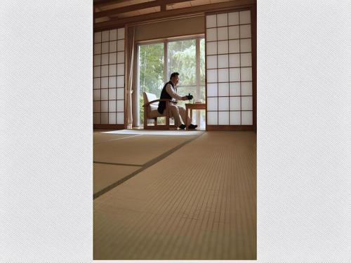 a man sitting in a chair in a room with a window at Kyoto Keburikawa Hotel in Kameoka