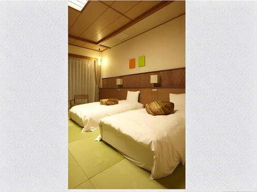 two beds in a hotel room with white sheets at Kyoto Keburikawa Hotel in Kameoka