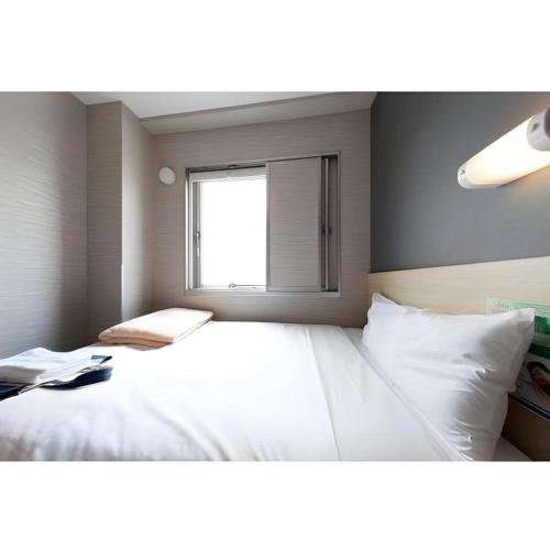 a bedroom with a large white bed with a window at Super Hotel Arai-Niigata in Myoko