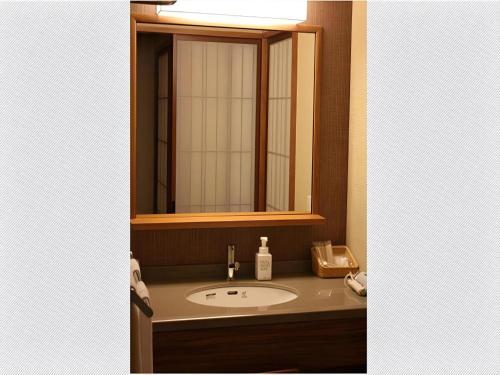 a bathroom with a sink and a mirror at Kyoto Keburikawa Hotel in Kameoka