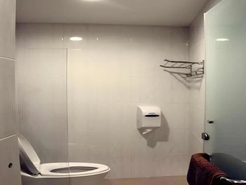 a bathroom with a toilet and a glass wall at Hotel Kristal in Seri Iskandar