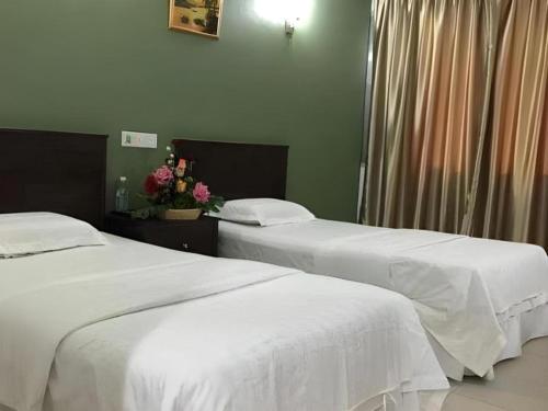 two beds in a hotel room with flowers on a table at Loong Fatt Hotel in Sungkai