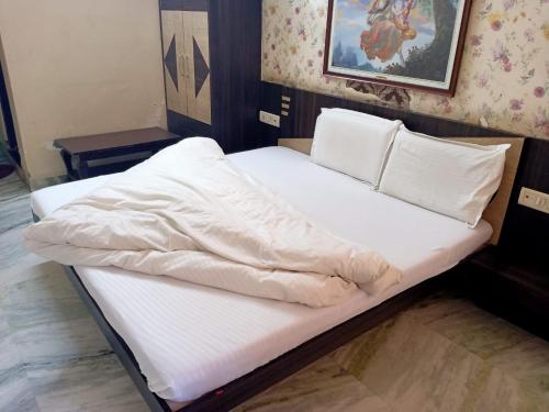 a bed with white sheets and pillows on it at Hotel Mukund and Restaurant in Nāthdwāra