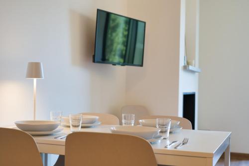 a dining room table with chairs and a tv on the wall at CaLolden in Ballabio