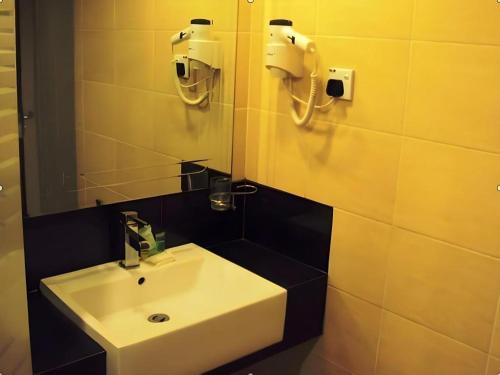 a bathroom with a white sink and a mirror at MB Hotel in Tawau