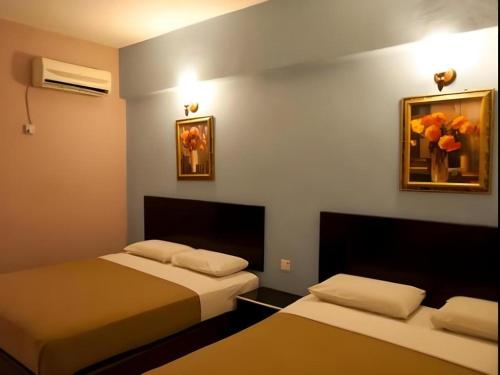 Una habitación con dos camas y un cuadro en la pared. en Hotel Ria, en Johor Bahru