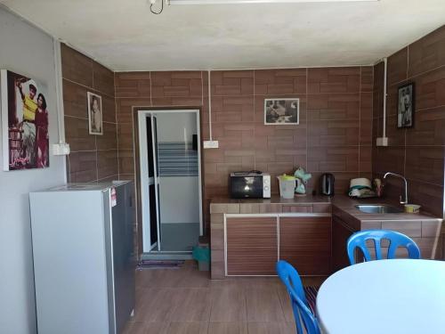 a kitchen with a refrigerator and a table with chairs at MyDesaStay in Sekincan
