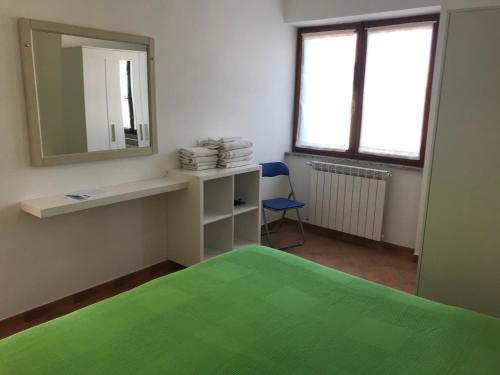 Habitación con cama verde y espejo. en Appartamenti Estivi Anna e Pino, en Rio Marina
