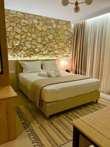 a bedroom with a large bed with a stone wall at Helios Sivota in Sivota