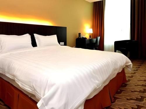 a large white bed in a hotel room at Eminent Hotel in Kota Kinabalu