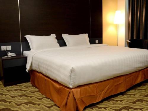 a large white bed in a hotel room at Eminent Hotel in Kota Kinabalu