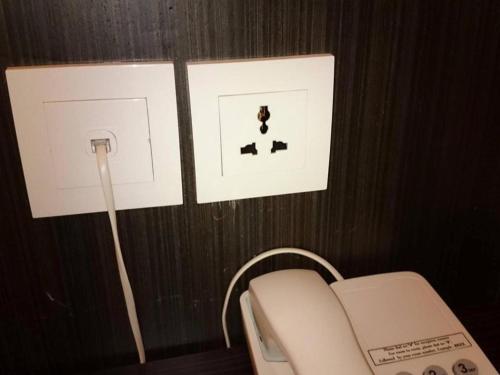 a white phone and two pictures on a wall at Eminent Hotel in Kota Kinabalu