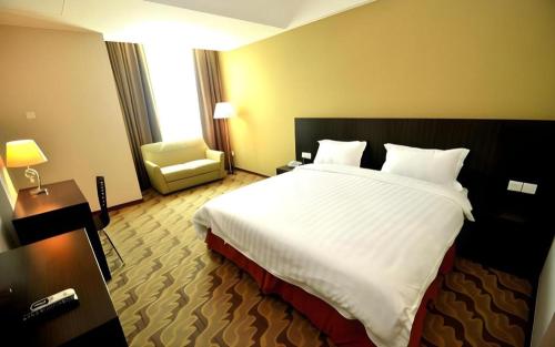a hotel room with a large bed and a chair at Eminent Hotel in Kota Kinabalu