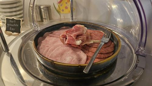 a bowl of ham in a microwave with a fork at Altes Pfarrhaus Hotel und Restaurant in Bad Überkingen