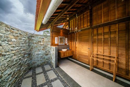 a bathroom with a sink and a stone wall at Kubu Sakian Villa and Restaurant Sidemen in Silebeng