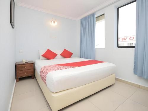 a white bedroom with a bed with red pillows at OYO 969 Hotel Pantai View in Labuan