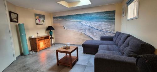 a living room with a blue couch and a painting of a beach at Alpaca World Friesland in Workum