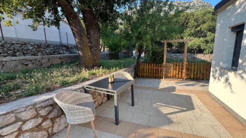 a table and chairs on a patio with a tree at MOREBIT - between sea and mountains, Cozy apartment with fireplace and heating in Vidovac