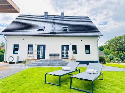 a white house with two chairs in front of it at Ferienhaus zum See Sonnenglanz in Funfseen