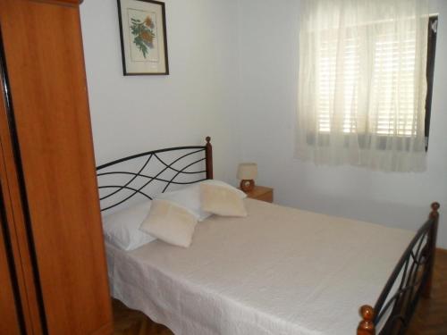 a bedroom with a bed with white sheets and a window at Apartments Maria in Tisno