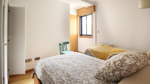 a bedroom with a bed and a chair and a window at AG Ático dAmalia Carballo in Carballo
