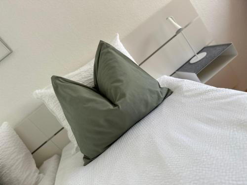 a green pillow sitting on top of a bed at Studio Breiti mit separatem Eingang in Pratteln