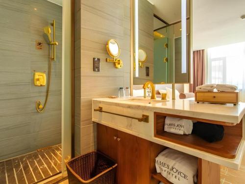 a bathroom with a sink and a mirror and a shower at James Joyce Coffetel Aletai Lanwan Food City in Pei-t'un