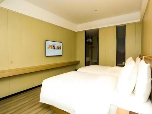 a bedroom with two beds and a television on the wall at Borrman Hotel Xiamen Xiang'an Maxiang in Xiamen