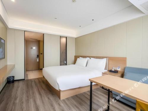 a hotel room with a bed and a table at Borrman Hotel Xiamen Xiang'an Maxiang in Xiamen