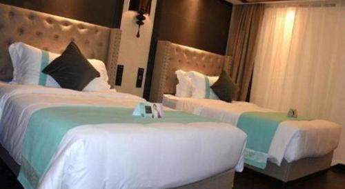 two beds in a hotel room with white and green at Xana Hotelle Zhuhai Gongbei Port in Zhuhai