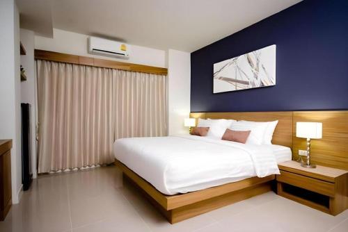 a bedroom with a white bed and a blue wall at Pannapat Place in Bangkok