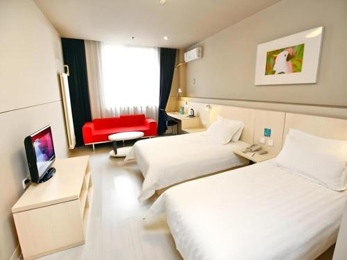 a hotel room with two beds and a red chair at JinJiang Inn Nanchang Bayi Square Ximazhuang Food Street in Nanchang