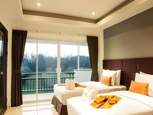two beds in a hotel room with a balcony at Amin Resort in Ban Thalat Choeng Thale