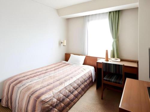 a bedroom with a bed and a desk and a window at Marroad Inn Tokyo in Chofu