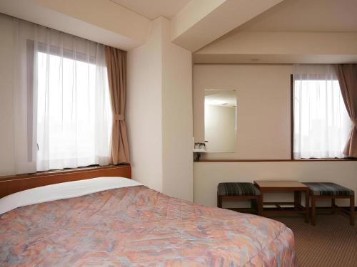 a bedroom with a bed and two windows and a table at Marroad Inn Tokyo in Chofu