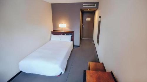 a bedroom with a large white bed in a room at Hotel Areaone Miyazaki in Miyazaki