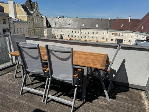 a wooden table and two chairs on a balcony at Klimatisierte Luxus-Dachterrassenwohnung im Zentrum in Sankt Pölten