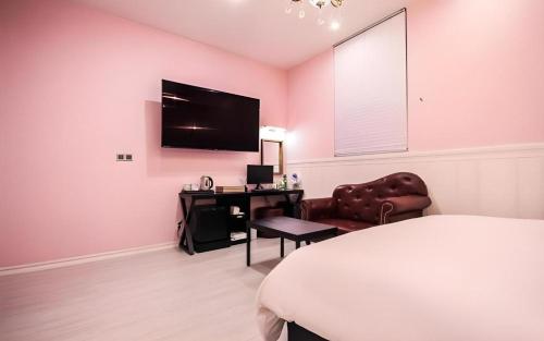 a bedroom with a bed and a desk and a television at Hotel Seowa in Gimhae