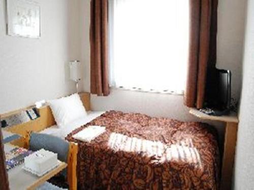 a small bedroom with a bed and a window at Hotel Castle Plaza in Kobe