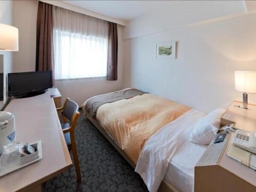 a hotel room with a bed and a desk at Hotel Castle Plaza in Kobe